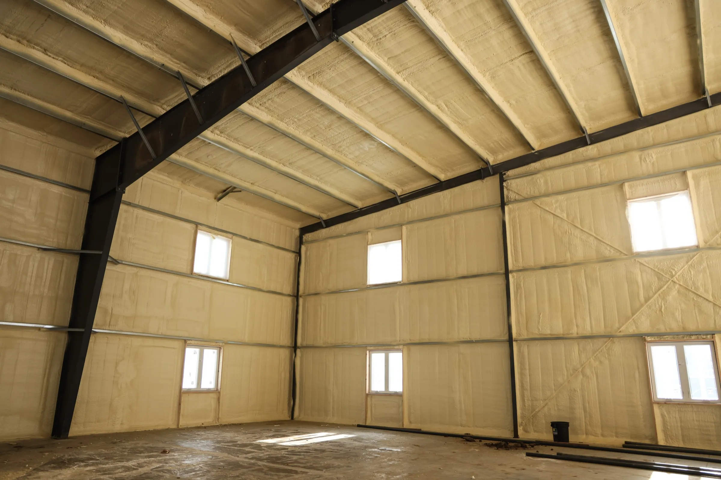 Metal building interior with sprayed walls and high windows